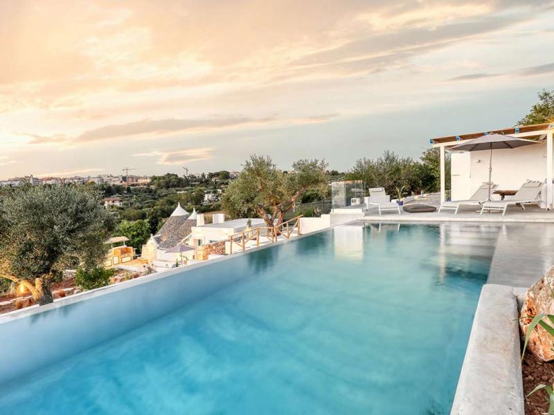 Piscina a sfioro con vista panoramica su una città e colline circostanti.